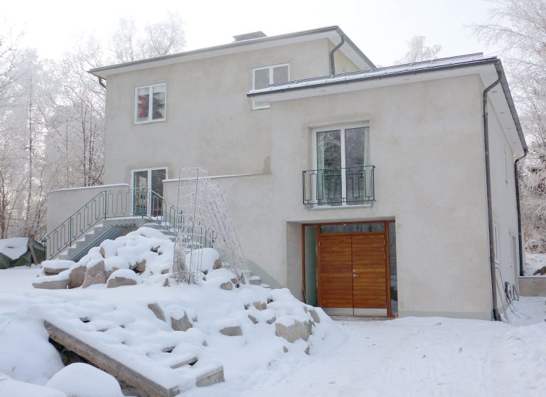 Vacker ytterdörr i trä med sidoljus på hus med putsad vit fasad