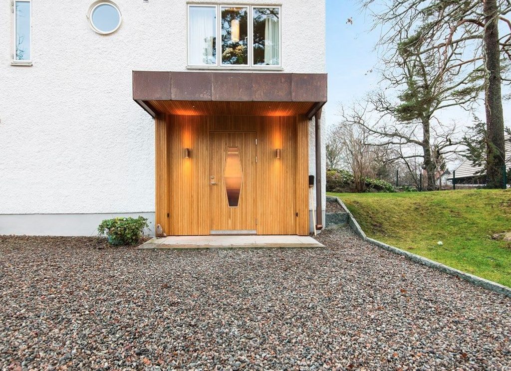 Entreparti i ek till hus med putsad fasad