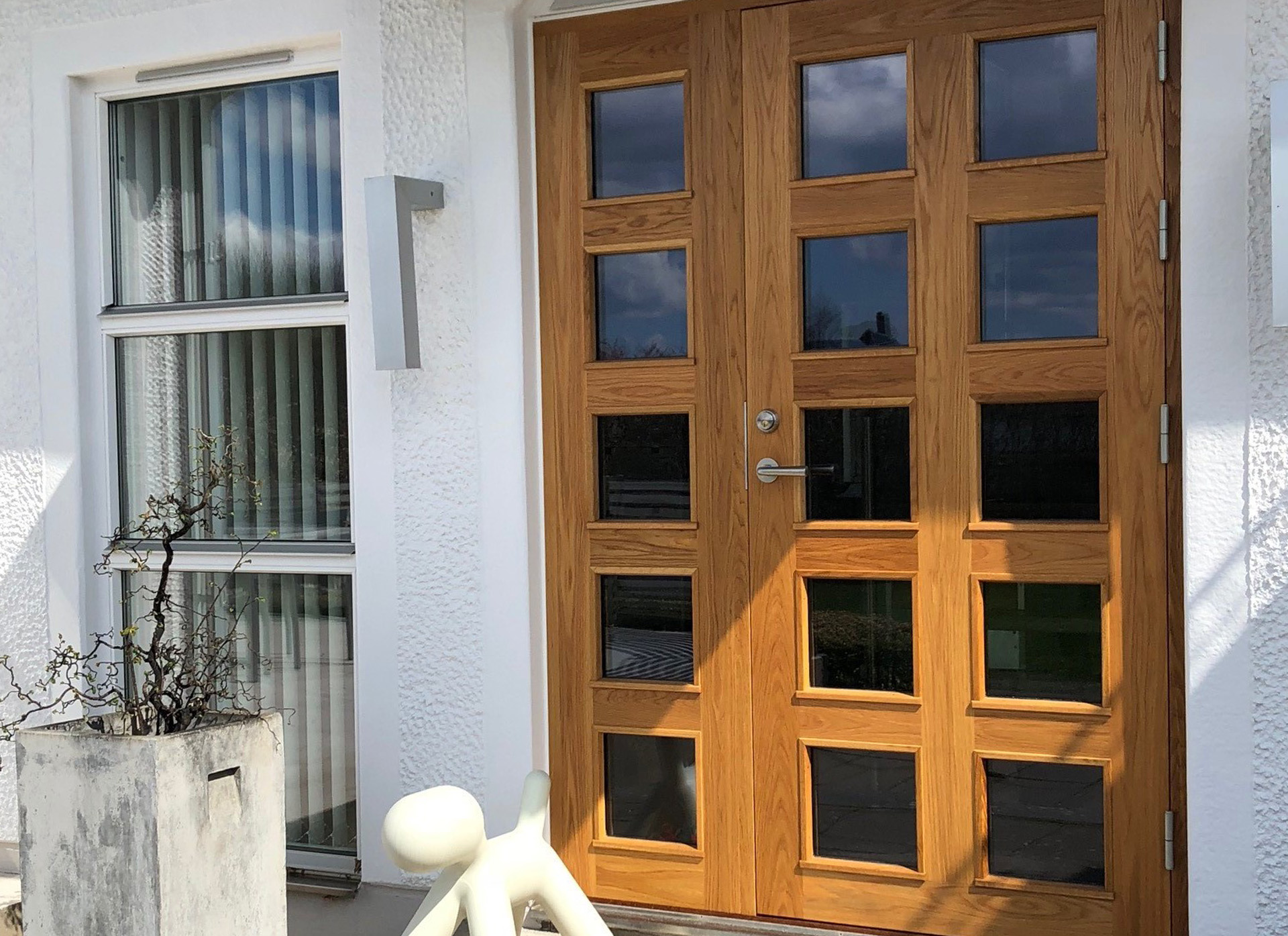 Ytterdörr i teak med glas till hus med putsad fasad